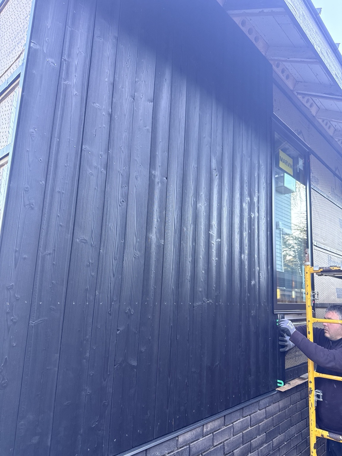 Black vertical siding and thin-brick veneer being installed on our Green Lake exterior project